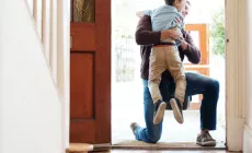 Un jeune garçon se précipite dans les bras de son père à la porte d'entrée.